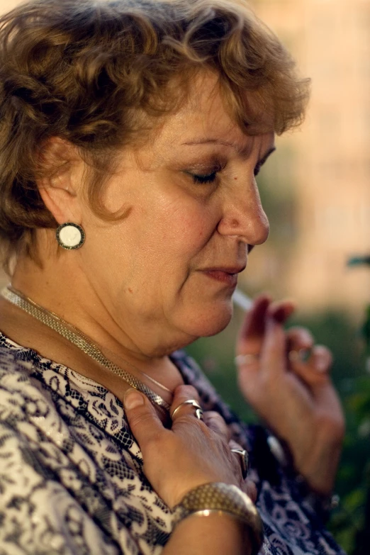 a woman wearing statement ear rings smoking a cigarette