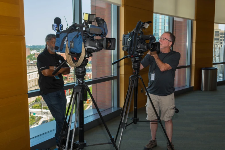 two men standing in front of a window with a camera