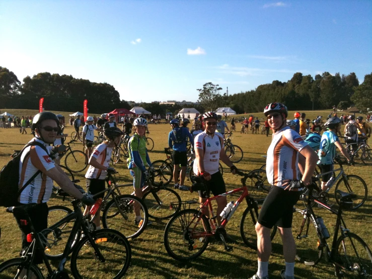 several people on bikes parked on a field near trees