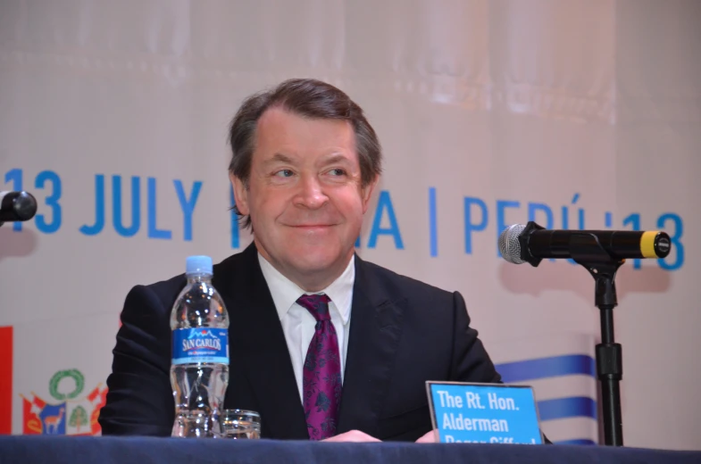 a man sitting at a podium with a bottle of water