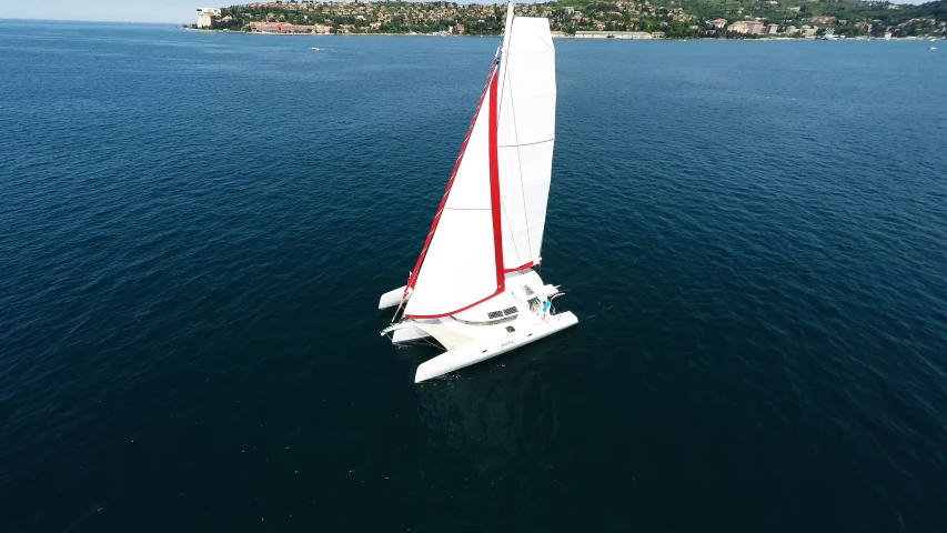 a white sailboat with red trim sailing in a body of water