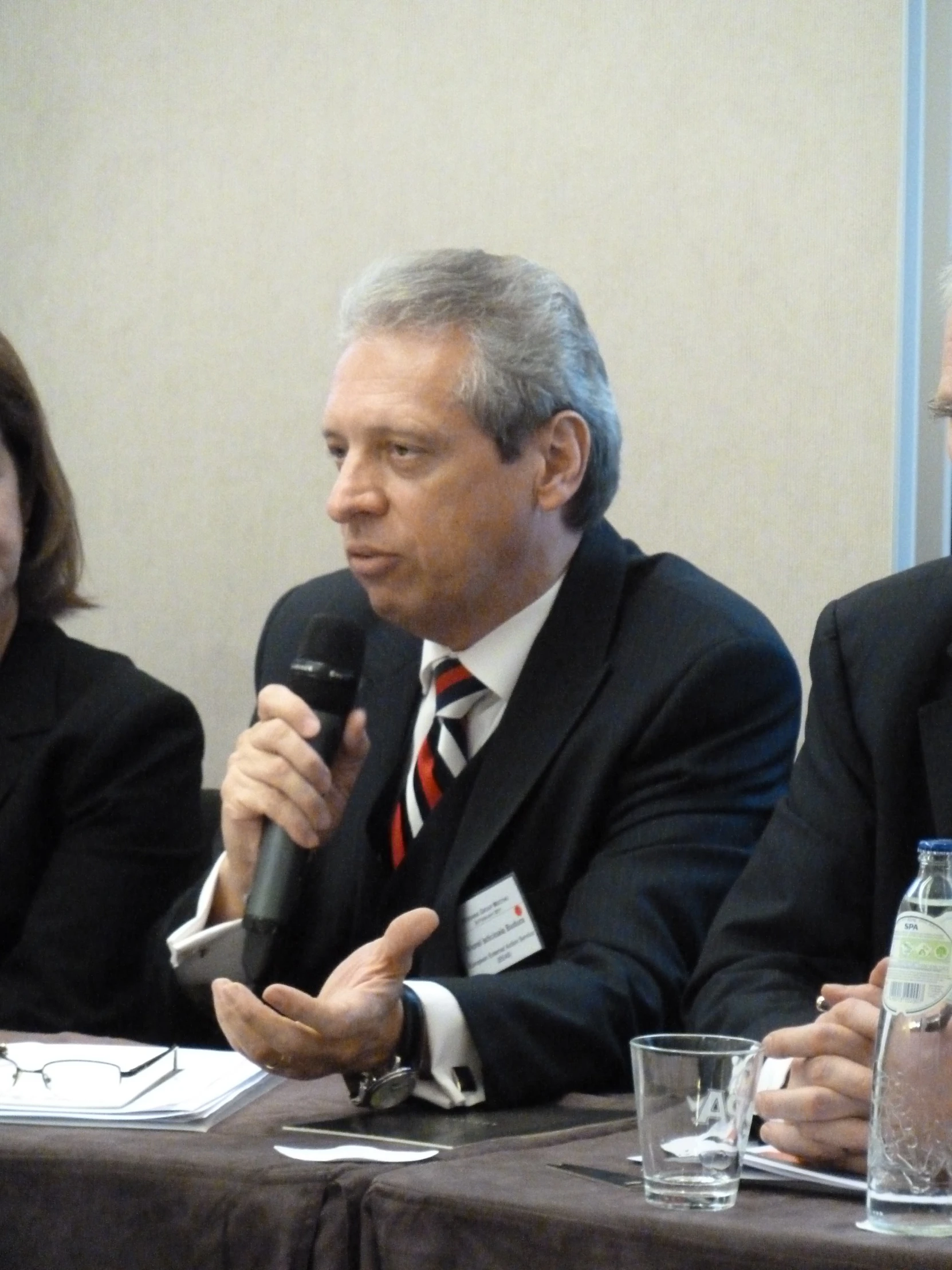 three men and one woman speaking into microphones in front of the people