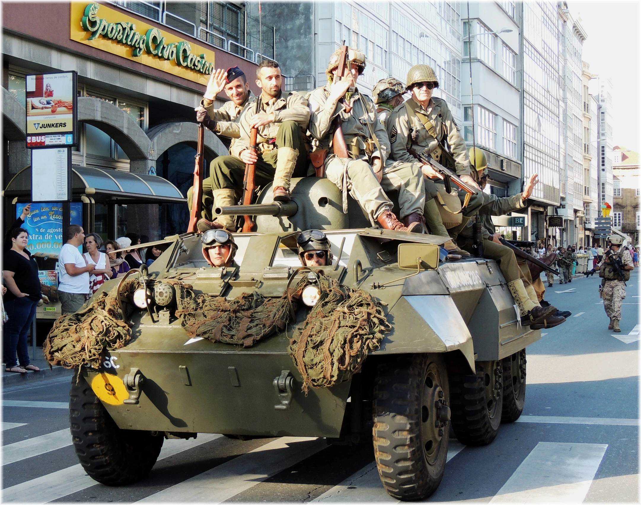 several people sit atop of a army tank