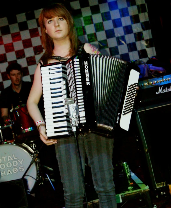 a woman holding a accordion next to a drum