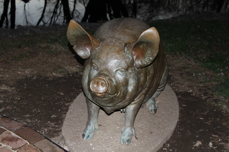 a statue of a small pig standing on top of a stone