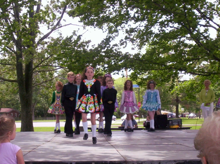 s dressed in folk clothes on stage with trees