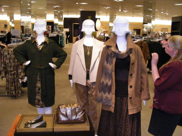 four mannequins dressed in brown and black, stand in an open shop