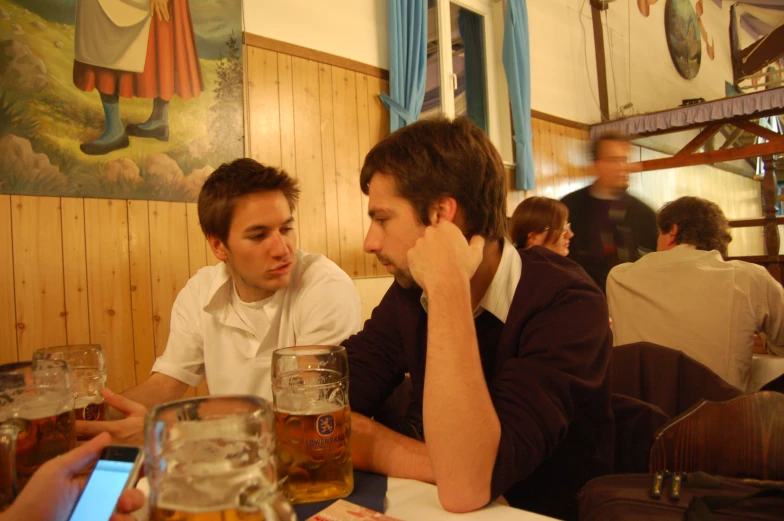 two men sitting at a table with several beers in front of them