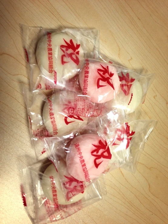 six decorated cookies in plastic wrap on a wooden table