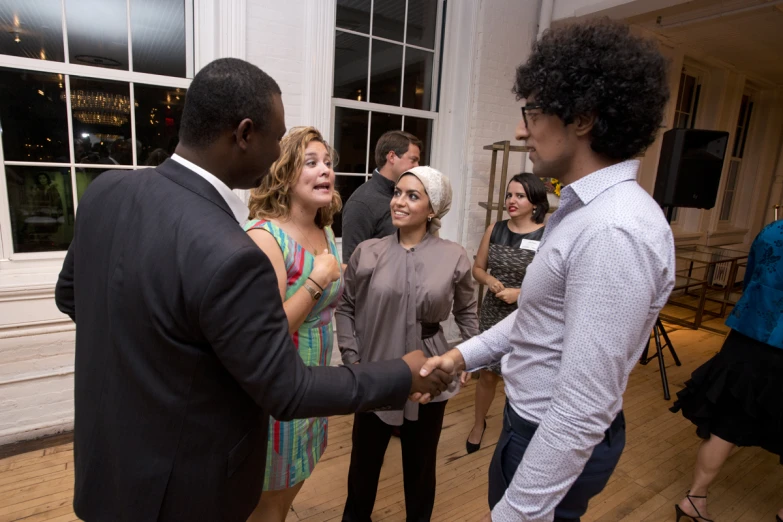 two young men shaking hands with other young people