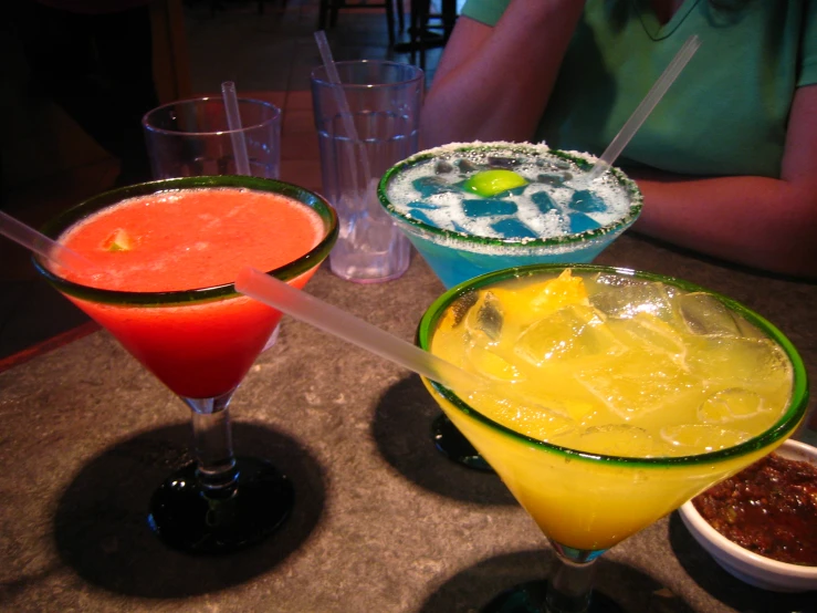 three different colored cocktails sitting on top of a table