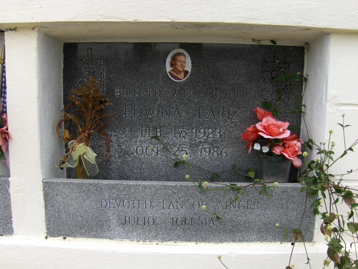 a small memorial in front of a building with flowers on it