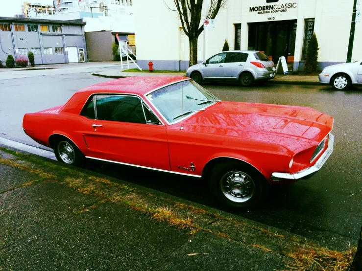 an old red car is parked near a curb