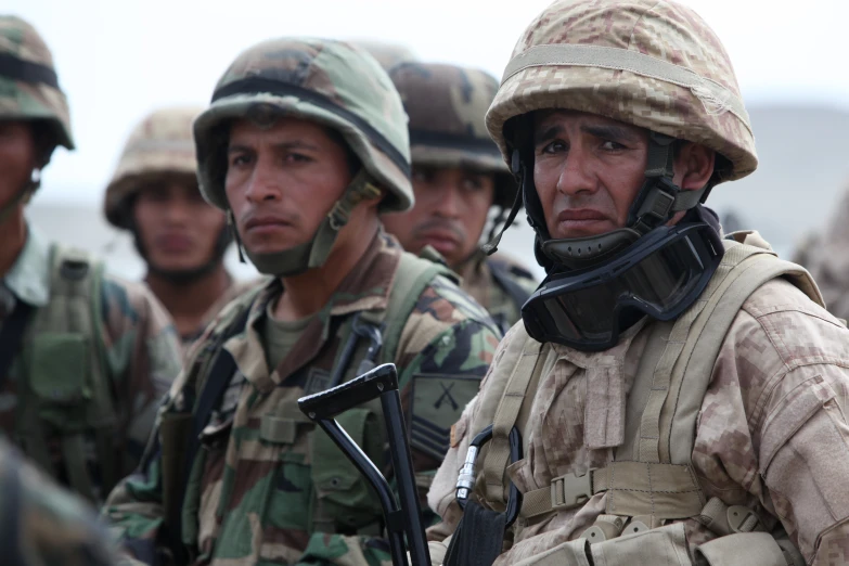 a group of men in military uniform and helmet, one of them has a gun