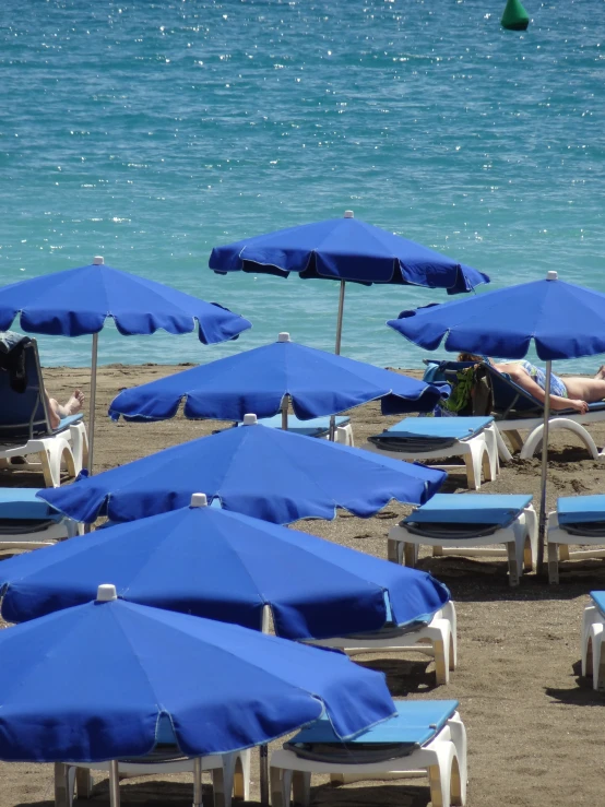 the blue umbrellas are covering the beach chairs