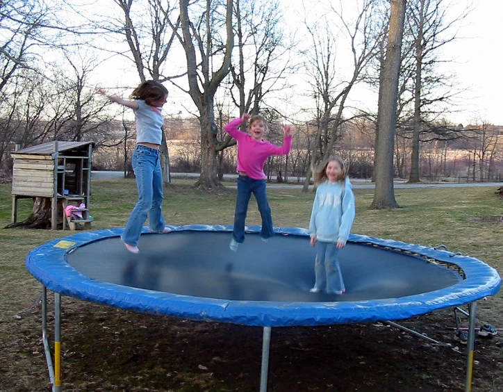 two children standing on a trampoline in a park