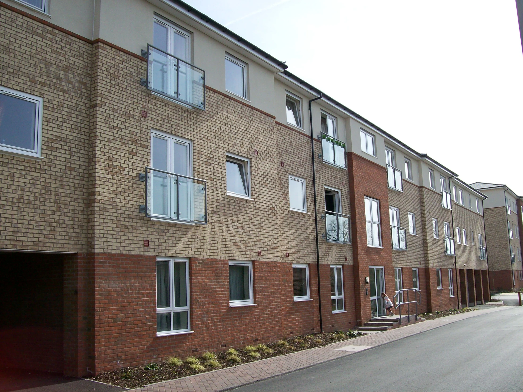 a tall brick building with windows and bushes on the side