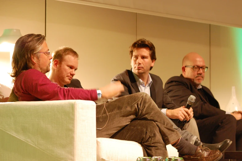 a couple of people sit together on chairs with microphones