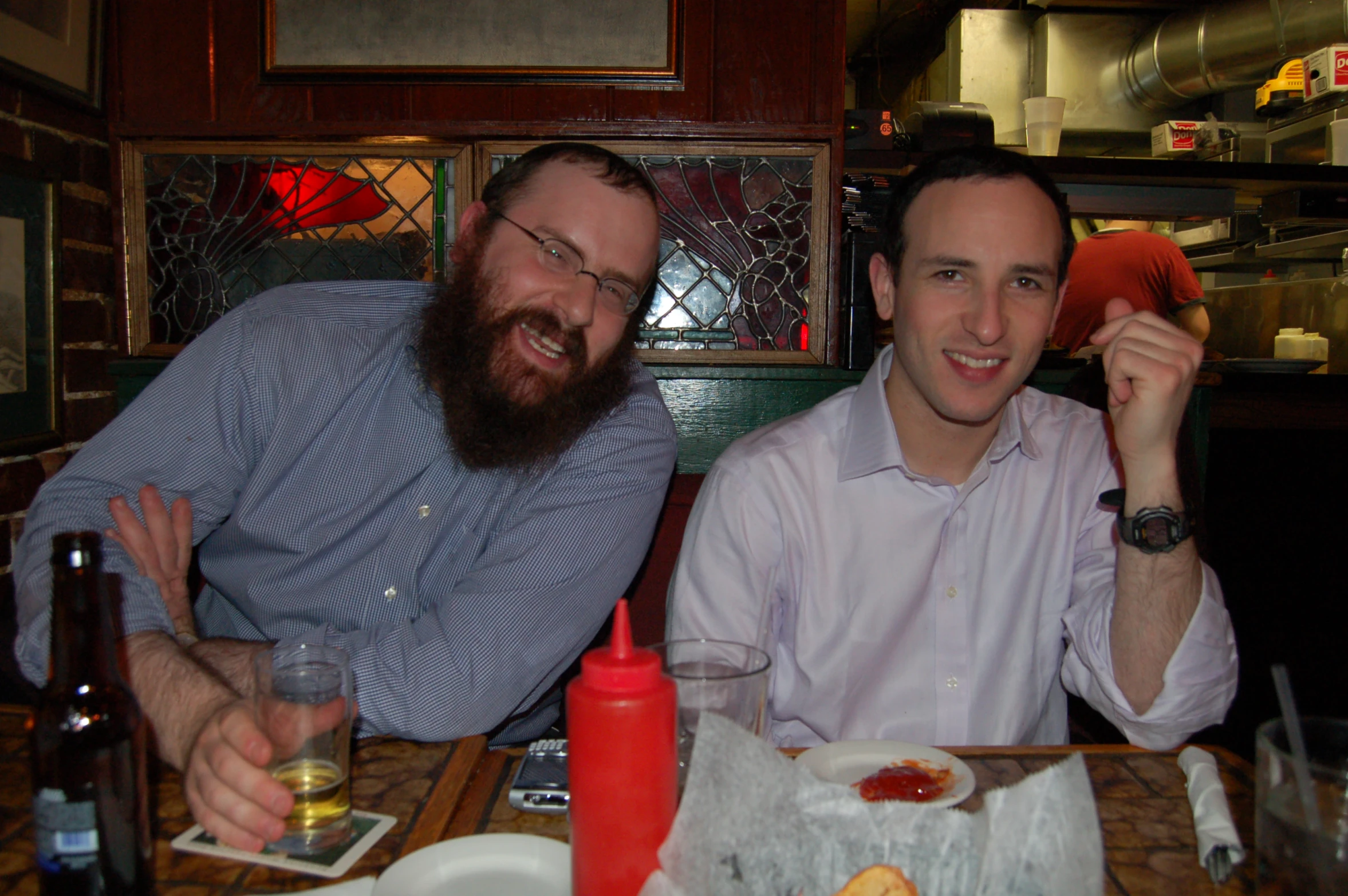 two men sit together at the table in front of bottles