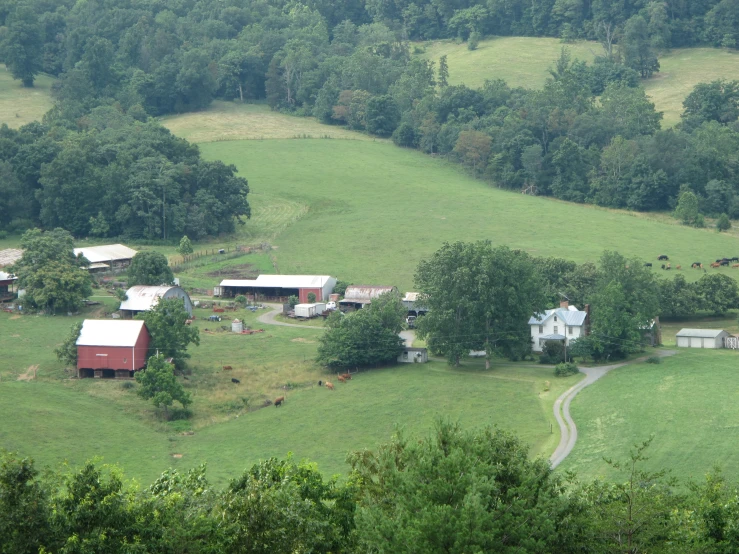 a farm nestled on top of a hill with many trees