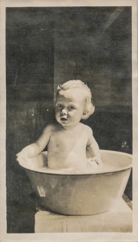 a very old black and white po of a very small baby in a big tub