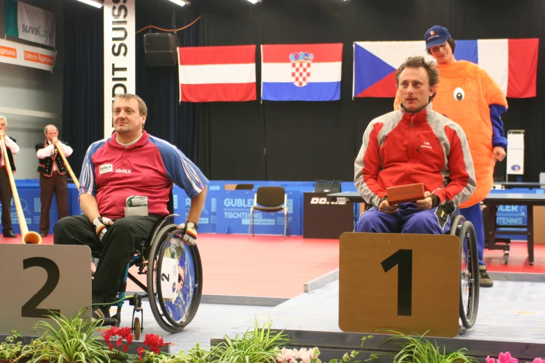 two men with wheels on their backs sitting in wheelchairs