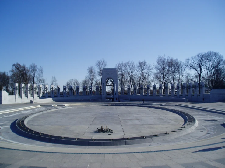 a circular stone with benches, trees and clock tower in the background