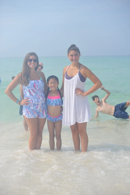 two women and two girls in swimsuits standing at the beach