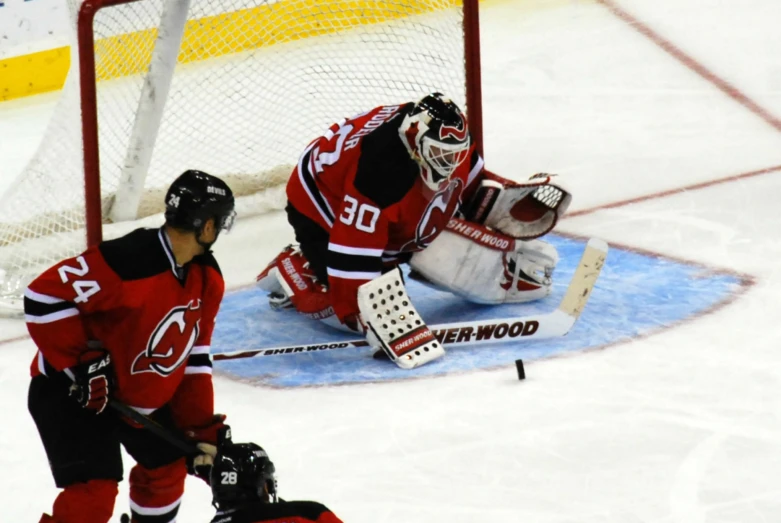 hockey goalie makes an effort to stop the puck from reaching out