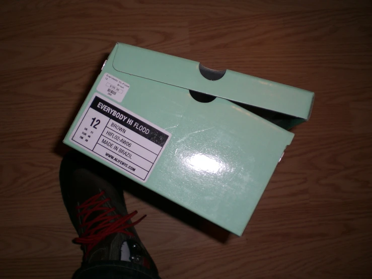 a green box on top of a table with a pair of red shoes inside it
