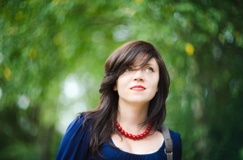 woman in blue shirt wearing a red necklace