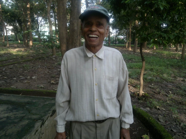 a man smiling in front of some trees