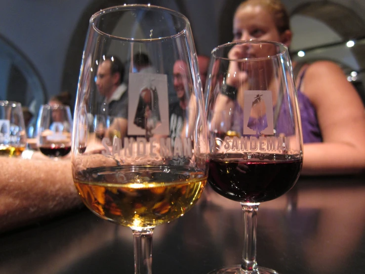 two glasses of wine sit on the bar while a woman takes a selfie