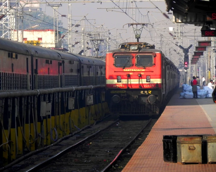 a train station with a few trains on the tracks and people walking along the platform