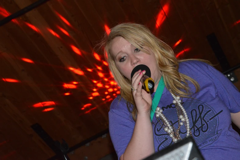 a woman eating donut with colorful lights in the background