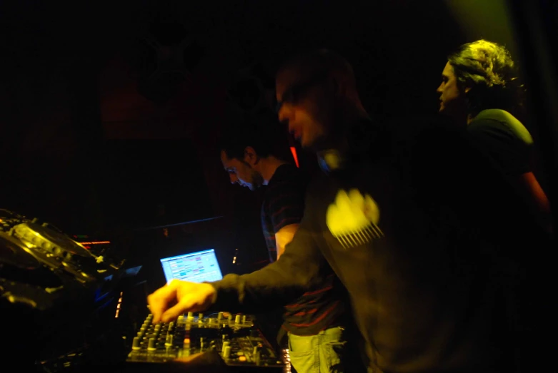 two men at work in the dj booth with headphones on