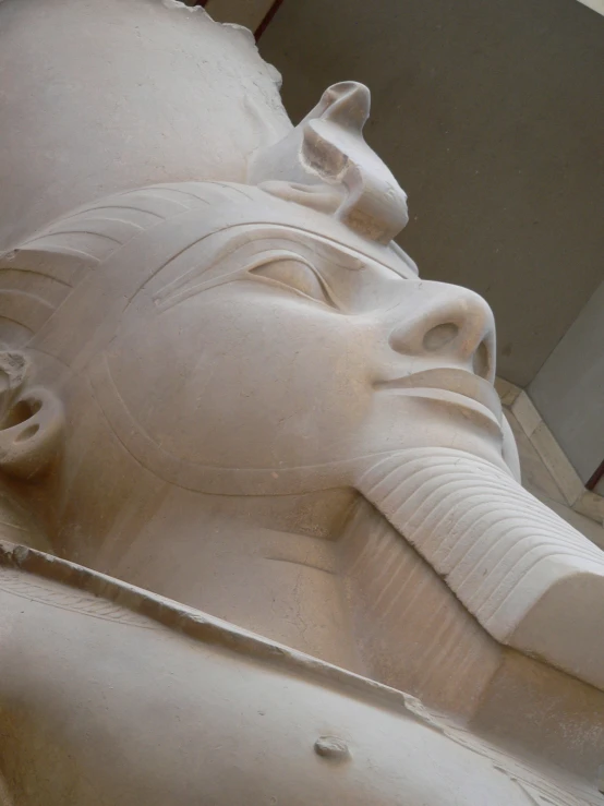 the head of an ancient statue sits next to a wall