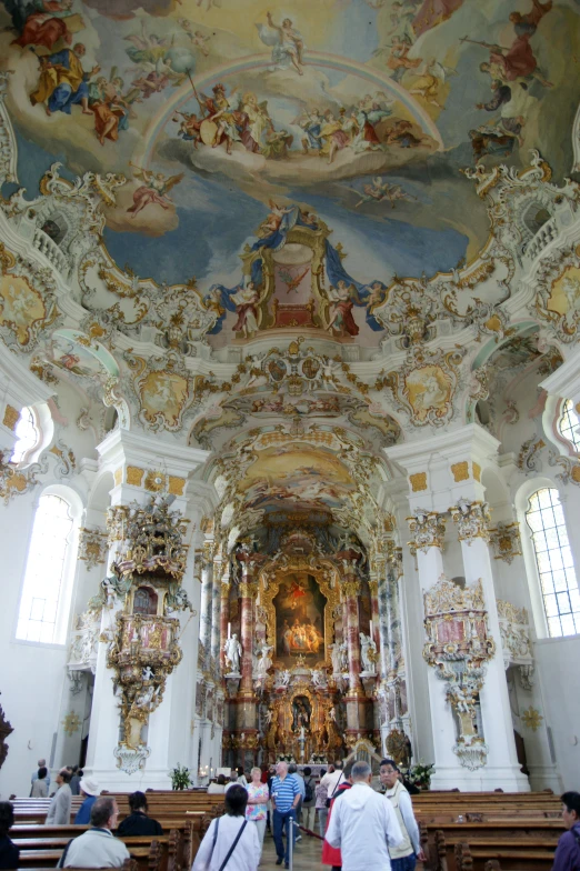 people are inside of a church with some large paintings on the walls