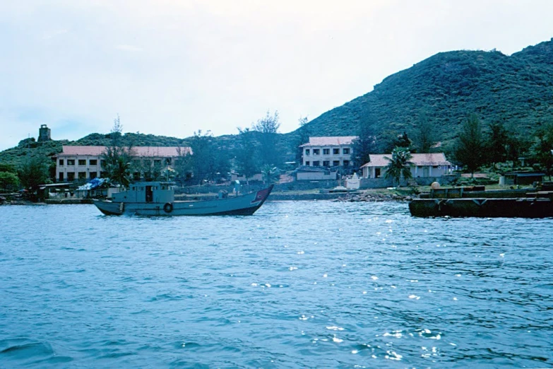 a small boat is passing by a few village homes