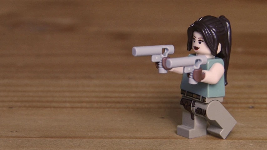 a lego figure is holding a gun with a smaller lego figure