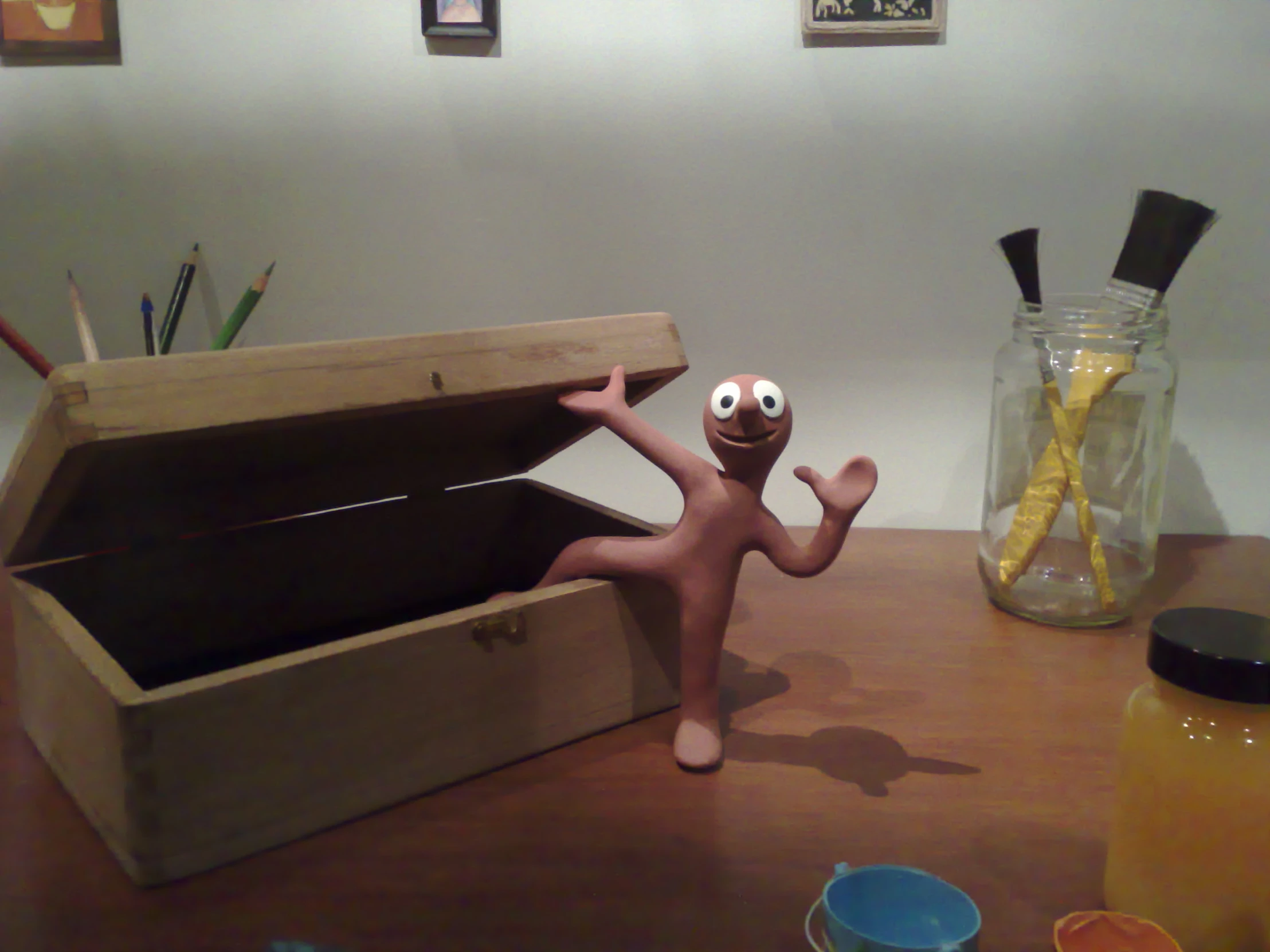 a wooden toy on a table with two jars, some spoons, a vase and an empty container in the box