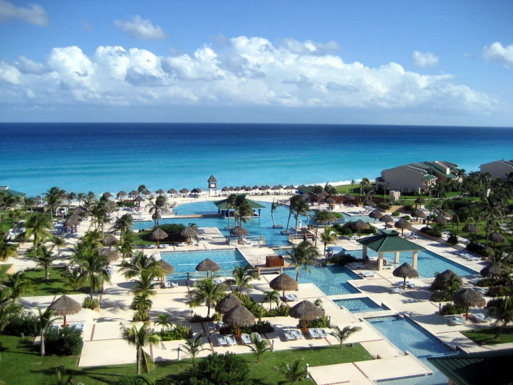 an aerial view of a resort pool and beach with lounge chairs