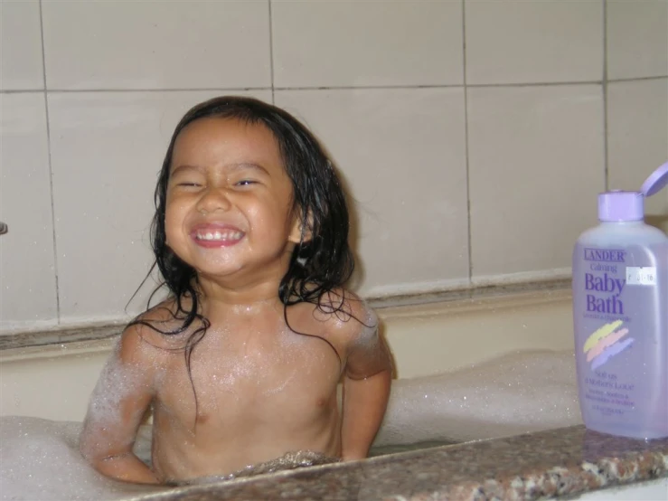 a child sitting in a bath tub with foam and soap
