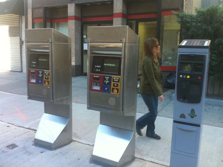 two women walk by the cash machines on the sidewalk