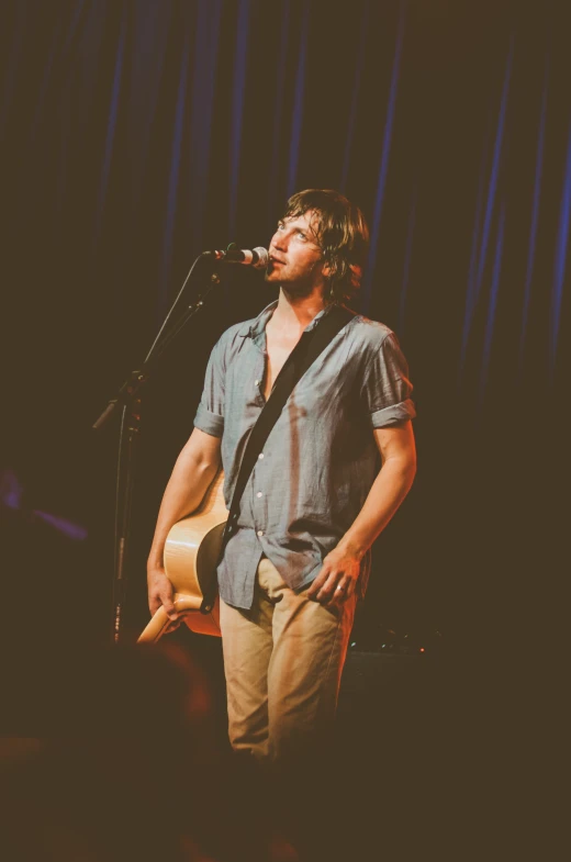 a man standing in front of a microphone with a guitar on his chest