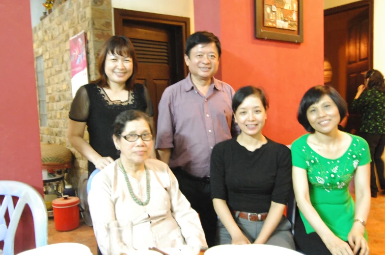 people standing and sitting around a table smiling for the camera