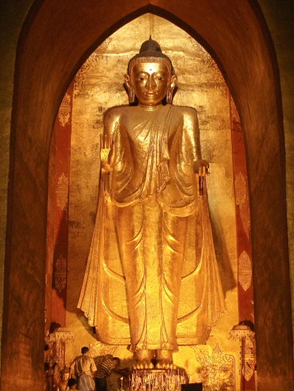 a large buddha in an intricate setting with a man sitting
