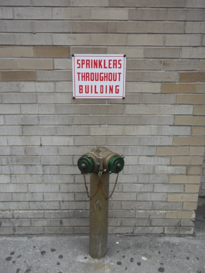 a fire hydrant on a sidewalk next to a brick wall