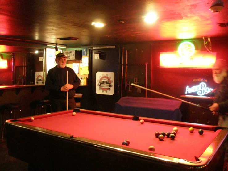 a person standing at a pool table with a neon sign