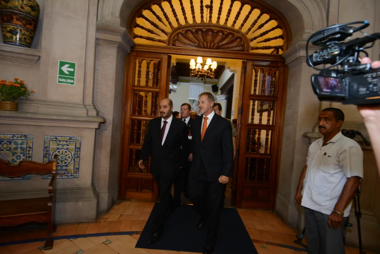 three people in suits stand on a ramp